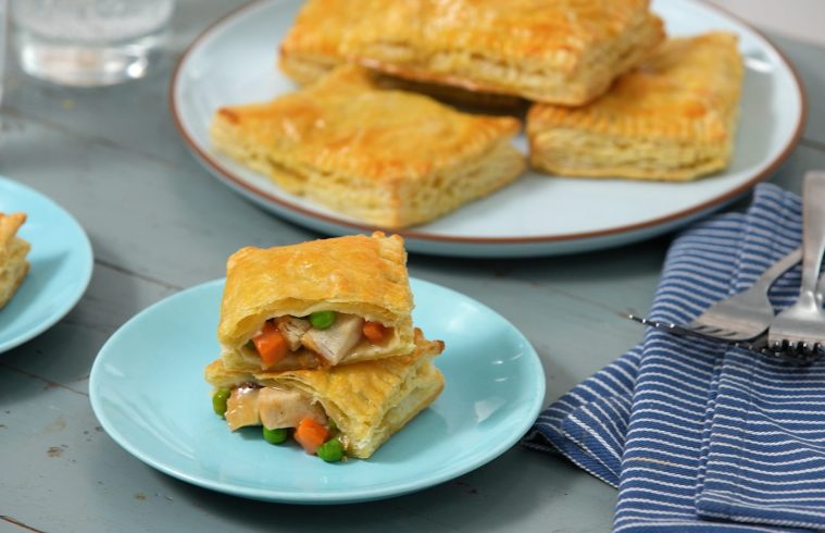 Image of chicken pot pie pockets on plates with one cut open showing meat, veggies and gravy inside