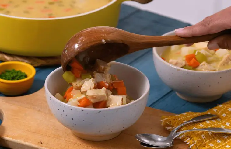 Ladeling Creamy Chicken Potato Chowder into soup bowls