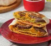 A completed Steak Fajita Crunchwrap on a red plate in a place setting