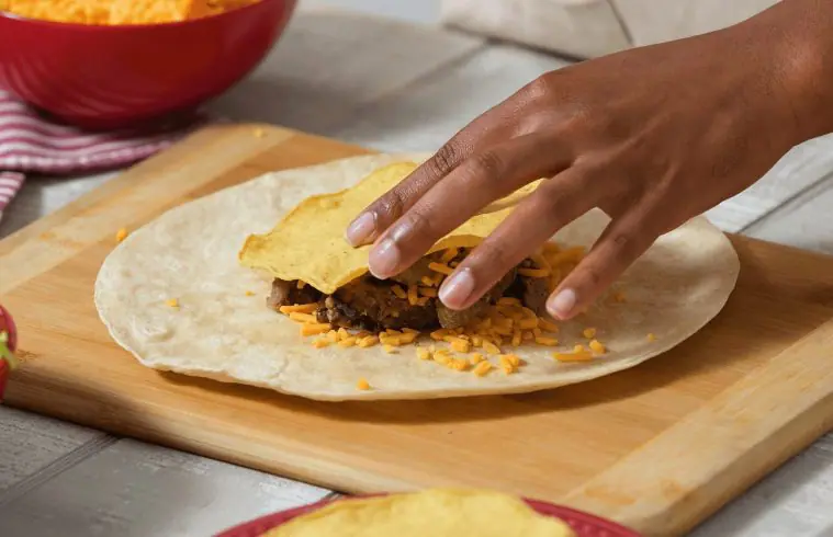A person's hands assembling a Steak Fajita Crunchwrap